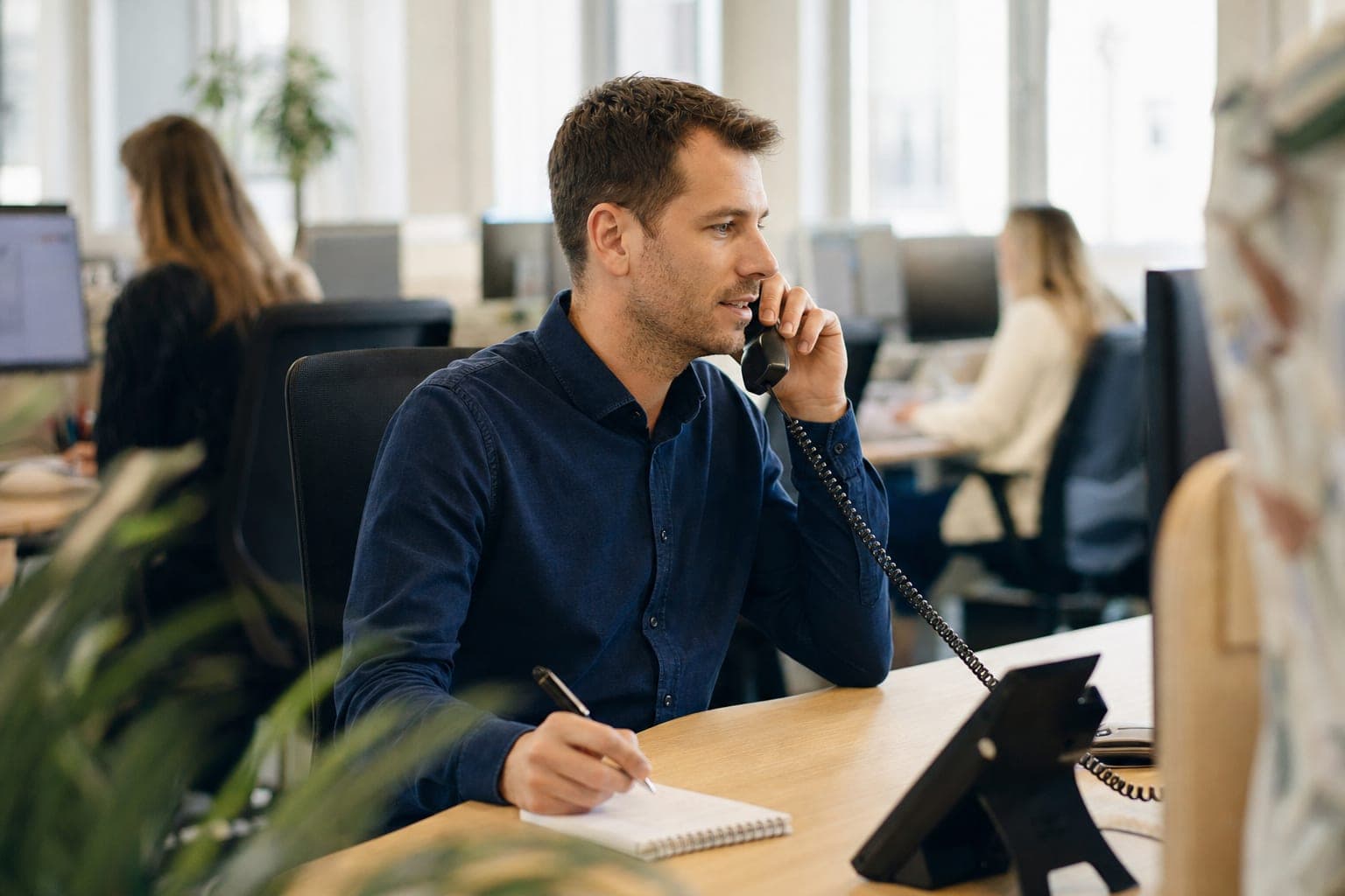 Recruiter im Büro am Telefon, daneben Notizblock und Tischapparat